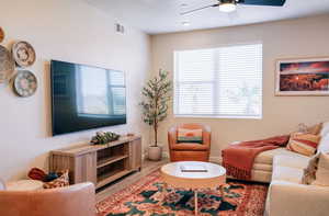 Living room with a ceiling fan, wood finished floors, and a textured ceiling