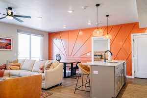 Kitchen featuring open floor plan, light countertops, light wood-style floors, a breakfast bar area, and a textured ceiling