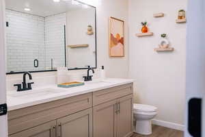 Bathroom featuring double vanity, wood finished floors, an enclosed shower, and recessed lighting