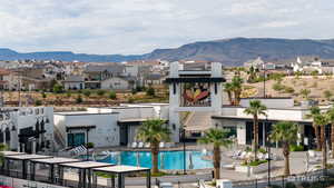 Back of house featuring a residential view, a mountain view, a community pool, and stucco siding
