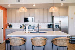 Kitchen featuring light wood finished floors, recessed lighting, stainless steel appliances, a kitchen breakfast bar, and light countertops