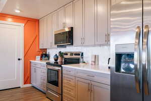 Kitchen featuring appliances with stainless steel finishes, light countertops, gray cabinetry, a textured ceiling, and light wood finished floors