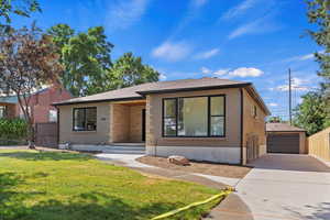 View of front of house featuring brick siding, an outdoor structure, driveway, and a detached garage