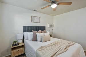 Carpeted bedroom featuring a wall mounted AC and ceiling fan