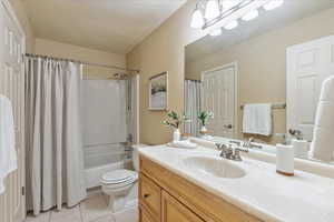 Bathroom with tile patterned floors, vanity, and shower / bathtub combination with curtain