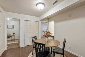Dining room featuring dark wood-style flooring and baseboards