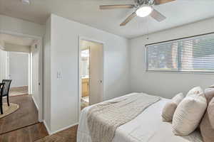 Bedroom with wood finished floors, connected bathroom, and a ceiling fan