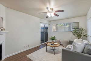 Living area with wood tiled floors, a fireplace, and a ceiling fan