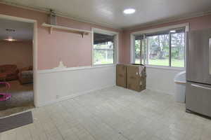 Unfurnished dining area with wainscoting and brick patterned floors