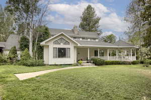 Rear view of house featuring a lawn, a chimney, and a porch