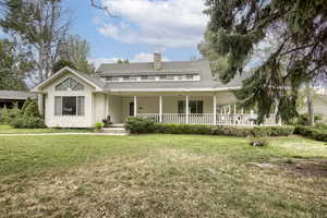 View of front facade with a porch, a chimney, a front yard, and roof with shingles