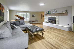 Living area with light wood-style flooring, a fireplace, and wooden walls