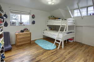 Bedroom featuring multiple windows, wood finished floors, and lofted ceiling