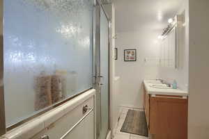 Full bathroom with vanity, a stall shower, and tile patterned flooring