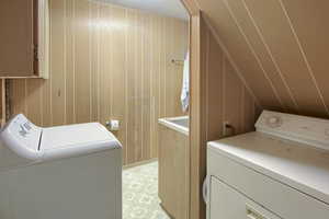 Washroom with washer and clothes dryer and wooden walls