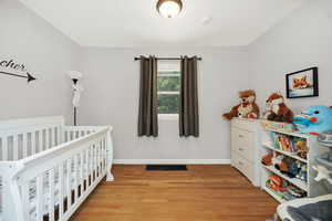 Bedroom with light wood-style floors and a nursery area