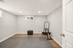 Exercise area with wood finished floors and recessed lighting
