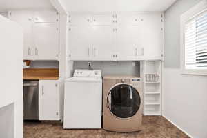 Washroom featuring independent washer and dryer, stone finish floors, and cabinet space