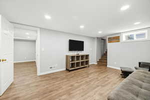 Living room featuring light wood-type flooring, recessed lighting, and stairs