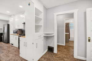 Kitchen featuring white cabinetry, appliances with stainless steel finishes, light countertops, open shelves, and recessed lighting