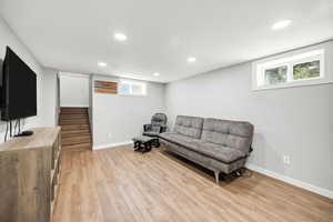 Living room featuring light wood-style flooring, recessed lighting, and stairway