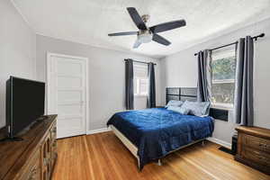 Bedroom featuring a textured ceiling, light wood-type flooring, and a ceiling fan