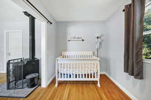 Bedroom with a wood stove and wood finished floors