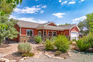 Ranch-style home featuring stone siding, roof with shingles, and an attached garage