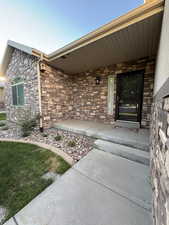 Entrance to property featuring stone siding and covered porch