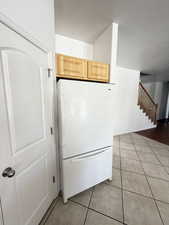 Kitchen featuring freestanding refrigerator, light tile patterned floors, and a textured ceiling
