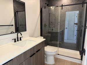 Bathroom featuring vanity, wood finished floors, and a shower stall