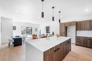 Kitchen with modern cabinets, light countertops, light wood finished floors, a kitchen island, and a textured ceiling