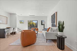 Living room featuring a textured ceiling, wood finished floors, stairs, and recessed lighting