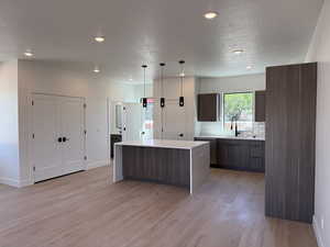 Kitchen with modern cabinets, healthy amount of natural light, light countertops, a kitchen island, and a textured ceiling