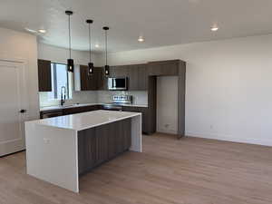 Kitchen featuring a center island, stainless steel appliances, modern cabinets, light wood-style flooring, and light countertops