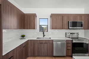 Kitchen with stainless steel appliances, modern cabinets, light wood finished floors, a textured ceiling, and decorative backsplash