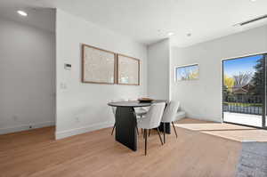 Dining area featuring recessed lighting, light wood finished floors, and a textured ceiling