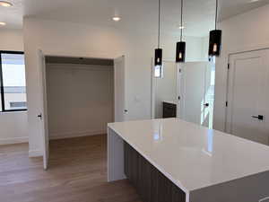 Kitchen featuring light wood-style flooring, recessed lighting, healthy amount of natural light, light countertops, and decorative light fixtures