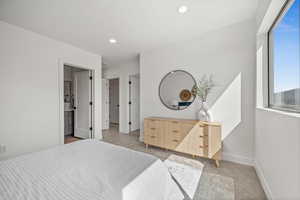 Bedroom with light colored carpet, recessed lighting, and ensuite bath