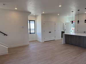 Kitchen featuring light wood-type flooring, a textured ceiling, light countertops, decorative light fixtures, and recessed lighting
