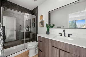Full bathroom featuring vanity, a textured ceiling, a shower stall, and wood finished floors