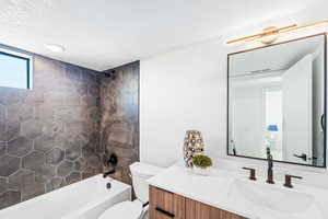 Full bath with vanity, a textured ceiling, and tub / shower combination