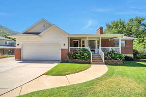 Ranch-style home with a garage, a front yard, a chimney, and brick siding