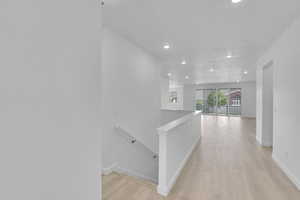 Corridor featuring an upstairs landing, light wood-type flooring, and recessed lighting