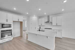 Kitchen featuring stainless steel appliances, white cabinets, light countertops, light wood-style floors, and recessed lighting