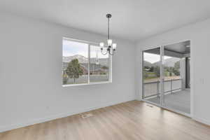 Unfurnished dining area with a mountain view, a chandelier, and wood finished floors