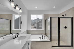Full bath with a bath, vanity, a stall shower, a mountain view, and healthy amount of natural light