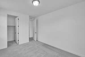 Unfurnished bedroom featuring carpet flooring and a walk in closet