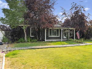View of front of home featuring a front yard and covered porch