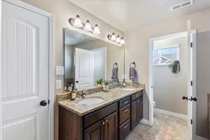 Full bathroom with double vanity and toilet